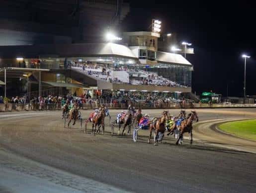 Carrera nocturna de caballos en el hipódromo con espectadores en las gradas