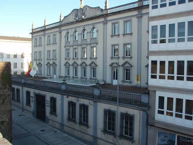 Vista exterior del Edificio Administrativo do Concello de Lugo con fachada clásica y banderas