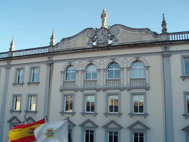 Detalle arquitectónico superior del edificio con escultura y balcón decorativo