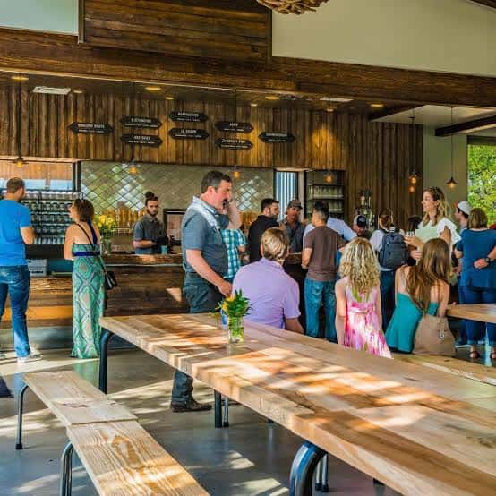 Ambiente interior del bar con clientes en mesas largas de madera