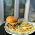 Plato gourmet con hamburguesa y papas fritas en ambiente elegante