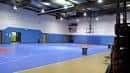 Vista interior de la cancha de baloncesto con suelo azul y canastas