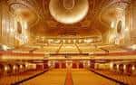 Interior del auditorio principal con techo ornamentado, balcones dorados y butacas rojas