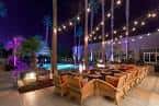 Área de eventos al aire libre con iluminación nocturna y mobiliario moderno