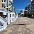 Vista diurna de la plaza empedrada con edificios residenciales modernos y escaleras blancas