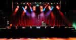 Escenario interior de Neumos con luces de concierto y cortinas rojas