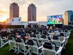 Vista panorámica del Rooftop Cinema Club Uptown en Houston al atardecer con butacas blancas y pantalla gigante