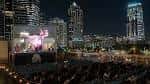 Escena nocturna del Rooftop Cinema Club Uptown con proyección en vivo y skyline de Houston iluminado