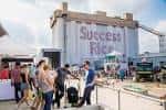 Vista exterior de los silos con el letrero 'Success Rice' y eventos al aire libre