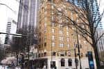 Fachada histórica del hotel durante el día con árboles y edificios modernos al fondo