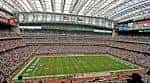 Vista interior del Reliant Stadium durante un evento deportivo con campo de fútbol americano y gradas llenas