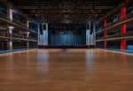 Escenario vacío con piso de madera y cortinas azules al fondo