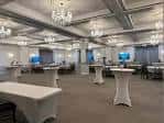 Vista general del salón de eventos con mesas altas y arañas colgantes