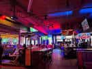 Interior del local con iluminación ambiental colorida y zona de mesas