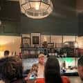 Área de bar en el Rec Room Arts con iluminación cálida y clientes