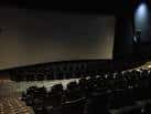 Interior de la sala de cine con butacas oscuras dispuestas en gradas frente a una gran pantalla