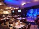Interior del Comedy Zone con escenario iluminado y mesas de comensales