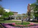 Vista panorámica de Market Square Park con jardines floridos y edificios urbanos al fondo