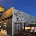 Fachada exterior de Soda Bar con murales artísticos y letrero iluminado
