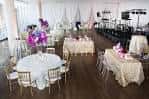 Salón de eventos decorado para recepción con mesas redondas, mantelería blanca y centros florales