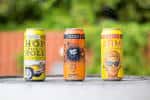 Tres latas de cerveza artesanal de NoDa Brewing Company en primer plano