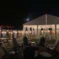 Terraza exterior iluminada por la noche con mesas y sillas