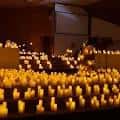 Interior del auditorio durante un evento con velas encendidas creando ambiente cálido