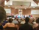Servicio religioso en curso con congregación y escenario con cruz