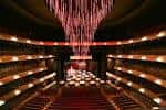 Interior del auditorio con butacas rojas y un gran candelabro de luces