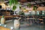 Interior del Lenny Boy Brewing Co. con mesas y barriles decorativos