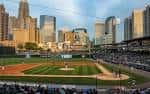 Campo de béisbol durante un partido con la ciudad iluminada por la tarde