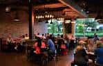 Interior del restaurante de Karbach Brewing Co. con clientes sentados en mesas bajo iluminación cálida