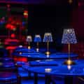 Mesas redondas con lámparas decorativas bajo luz ambiental azul