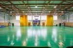 Vista interior del pabellón deportivo con pista verde y gradas amarillas