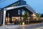 Vista exterior nocturna de HopFly Brewing Company con iluminación cálida y terraza
