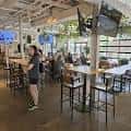 Interior del local con mesas altas, clientes sentados y ambiente relajado
