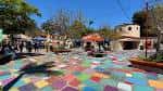 Espacio abierto con personas caminando y puestos de artistas en el centro