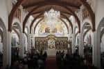 Vista general del interior de la iglesia con arcos de madera y congregantes sentados