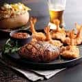 Plato de comida típica del restaurante: steak, camarones y papas asadas