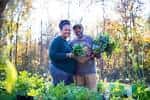Pareja sonriente sosteniendo canastas de vegetales frescos en un campo al aire libre