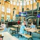 Interior del bar principal con mesas de picnic y ambiente industrial