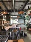 Interior industrial del local con barriles de cerveza, mesas altas y decoración moderna