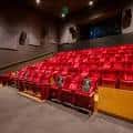 Interior del auditorio con butacas rojas dispuestas en gradas hacia el escenario