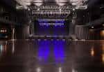 Escenario principal del auditorio con iluminación azul y piso de madera