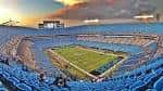 Interior del estadio durante el atardecer, mostrando las gradas vacías y el campo iluminado