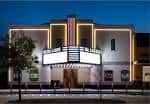 Fachada exterior del DeLUXE Theater iluminada por la noche