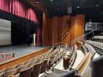 Interior del auditorio con butacas y escenario listo para eventos