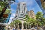 Torre de vidrio curvada rodeada de vegetación urbana en Tryon Street