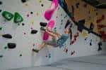 Escalador en acción sobre una pared de boulder con presas coloridas
