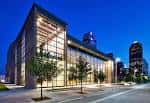 Vista exterior nocturna del Moody Performance Hall con fachada de cristal iluminada